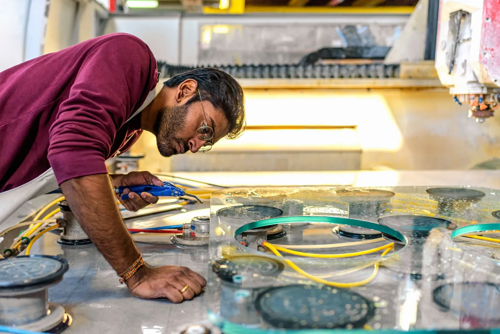 Mitarbeiter richtet eine Glasscheibe auf den Saugern des CNC-Tischs aus