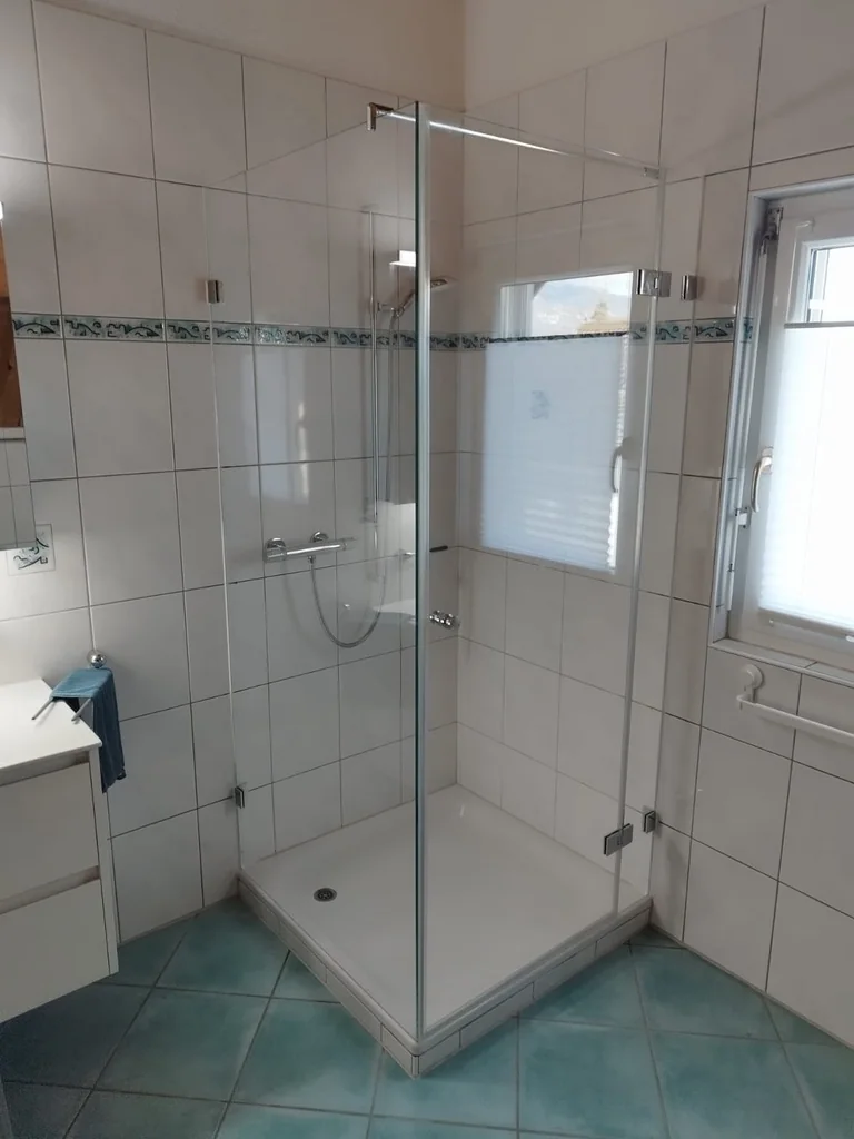 Eckdusche mit Tür und Seitenteil auf einer Duschwanne, von KURTH montiert